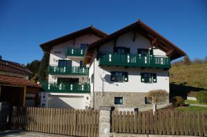 une maison blanche avec des balcons verts et une clôture dans l'établissement Bodenmaiser Herz-Hoamad Ferienwohnung Bierl, à Bodenmais