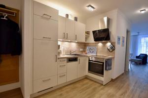 kuchnia z białymi szafkami i kuchenką w obiekcie VillaStrandEins Fewo Stella w mieście Rerik