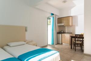 a bedroom with a bed and a kitchen with a table at Ibiscus Hotel Malia in Malia