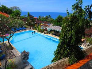 a large swimming pool with people swimming in it at Amed Cafe & Hotel Kebun Wayan in Amed