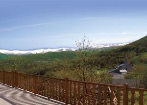 eine Holzbrücke mit schneebedeckten Bergen im Hintergrund in der Unterkunft Eido das Estrelas in Valdín