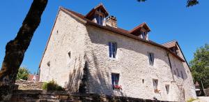 an old stone building with windows and a tree at La Tour Charlemagne in Château-Chalon