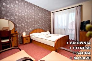 アウグストゥフにあるVilla Centrum Młodościのベッド、テレビ、ベッドルームが備わるホテルルームです。