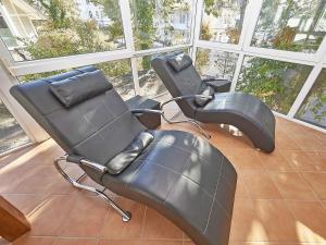 3 sillas negras en una habitación con ventanas grandes en Villa Saxonia - WG 13 mit Wintergarten, strandnah en Binz
