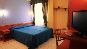 1 dormitorio con 1 cama azul y TV en Hotel Ristorante Umbria, en Orvieto