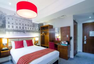 a hotel room with a large bed with red pillows at Seraphine Kensington Olympia in London