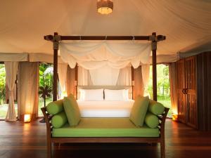 a bedroom with a canopy bed with a green couch at 9 Hornbills Tented Camp in Ko Yao Noi