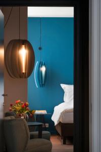 1 dormitorio con paredes azules, 1 cama y 1 silla en Zakske13 - Design Boutique B&B in Bruges city centre en Brujas