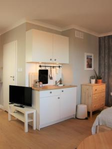 een keuken met witte kasten en een tv in een kamer bij Apartament Studio 208 in Biała Podlaska