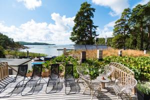 a deck with chairs and tables and a view of the water at Airisto Hill & Inn - Two Beach Cabins in Haverö