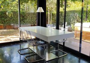 una mesa blanca y sillas en una habitación con ventanas en Appartement contemporain jardin & jacuzzi en Voisins-le-Bretonneux
