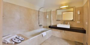 a bathroom with a tub, sink, mirror and bathtub at Regal Hotel in Brescia