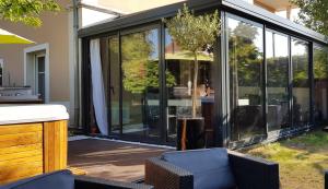 un salón acristalado con puertas correderas de cristal en un patio en Appartement contemporain jardin & jacuzzi en Voisins-le-Bretonneux