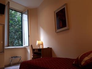 a bedroom with a bed and a desk and a window at Hotel Major Aventinus in Rome