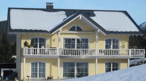 a large yellow house with a white balcony at Alpentraum in Riezlern