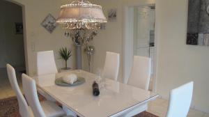 a white dining room table with white chairs and a chandelier at Alpentraum in Riezlern