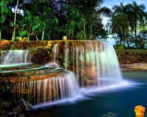 a waterfall in front of a pool of water at Paraiso Caño Hondo in Los Guineos Perdidos