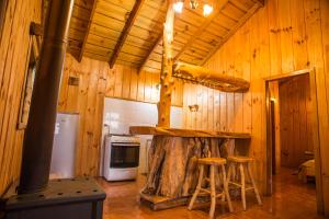 a kitchen with a stove and stools in a cabin at Apart hotel Puchaley Lafquen in Panguipulli