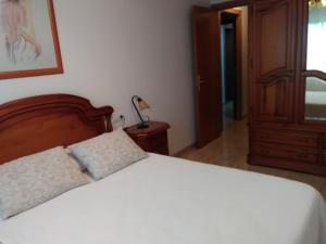 a bedroom with a white bed with a wooden headboard at Llastre in Hospitalet de l'Infant