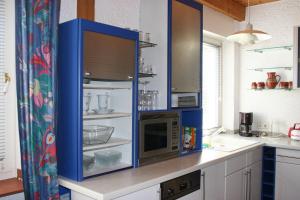 cocina con armarios azules y microondas en Ferienwohnung Bücker en Telgte