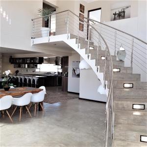 een eetkamer en een keuken met een trap en een tafel en stoelen bij Vogelstrand Holiday House in Swakopmund