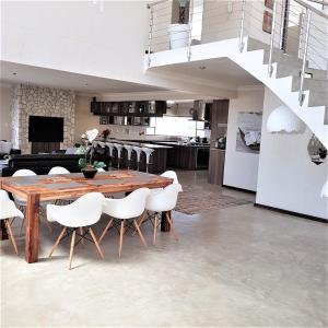 uma sala de jantar com uma mesa de madeira e cadeiras brancas em Vogelstrand Holiday House em Swakopmund
