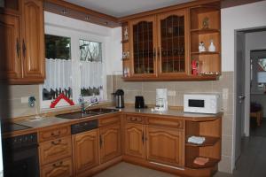 a kitchen with wooden cabinets and a sink and a microwave at Haus Swantje in Hinte