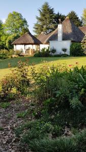 una casa con tetto in erba e un cortile fiorito di Piccadilly Farm Cottages a Lions River