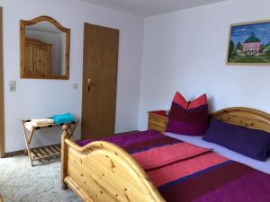 ラーデボイルにあるFewo Radebeul Altkötzschenbrodaのベッドルーム1室(紫色の枕が付いた大きな木製ベッド1台付)