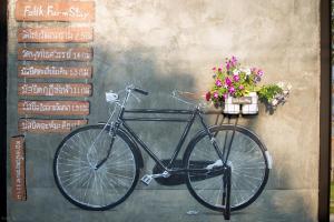 a bike parked next to a wall with flowers at Falik Farm Stay in Phra Nakhon Si Ayutthaya