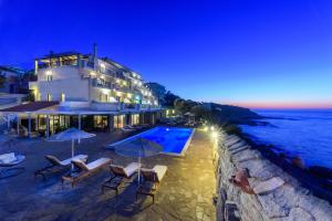 a hotel with chairs and umbrellas next to the ocean at Cavos Bay Hotel & Studios in Armenistis