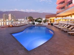 a swimming pool with lounge chairs and a building at Terrado Suites Iquique in Iquique