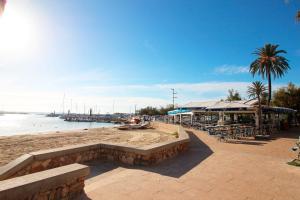 una playa con banco, mesas, sillas y agua en Apartaments Es Port ETVPL14335-13394, en Colonia de Sant Jordi