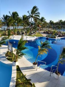 a large swimming pool with palm trees in a resort at Flat Summer House em Guarajuba in Guarajuba