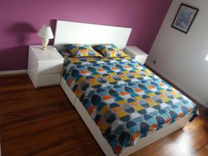 a bedroom with a bed with a colorful comforter at Varanda do Atlântico in Ponta Delgada