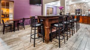 a bar with stools at a restaurant with purple walls at SureStay Plus Hotel by Best Western Kearney in Kearney