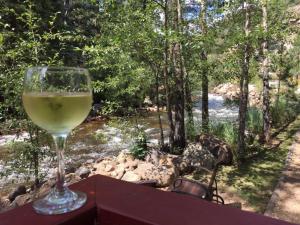 a glass of wine sitting on a table next to a river at Swiftcurrent Lodge in Estes Park