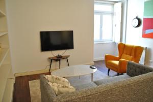 a living room with a couch and a table and a tv at Chiado 2 Bedroom Elegant Apartment in Lisbon