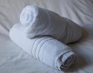 een opgerolde witte handdoek op een bed bij Lwr Ormeau Guest House in Belfast