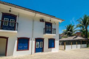 ein weißes Gebäude mit blauen Türen und einer Palme in der Unterkunft Pousada Lua Clara in Paraty