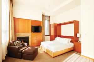 a bedroom with a bed and a chair and a tv at Pan Pacific Whistler Village Centre in Whistler