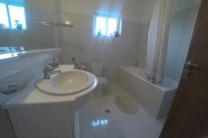 a white bathroom with a sink and a tub and a toilet at Oasis of CalmnessΕ in Ardánion +23 photos