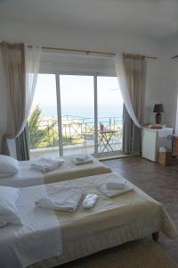 a bedroom with two beds with a view of the ocean at Akrotiri Hotel in Chania Town