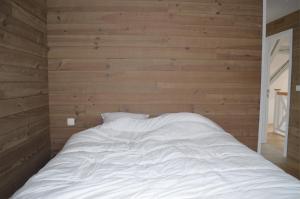 - un lit blanc dans une chambre dotée de murs en bois dans l'établissement la tourelle d’Achille leontine, à Rochefort