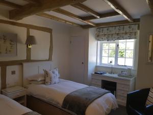 a bedroom with a bed and a desk and a window at Random Hall in Slinfold