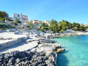 una playa con agua azul y rocas y edificios en Apartments Stepic, en Trogir