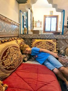 
a man laying on a bed with a blue blanket at Maison d'hôtes Cité Portugaise in El Jadida
