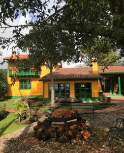 Una casa amarilla con un árbol delante. en Estancia San Antonio, en Guasca