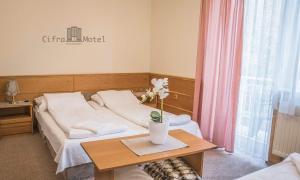 ein Schlafzimmer mit einem Bett und einem Tisch mit Blumen darauf in der Unterkunft Cifra Motel in Kecskemét
