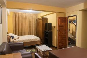um pequeno quarto com uma cama e uma televisão em La Maison Martinet em Uyuni